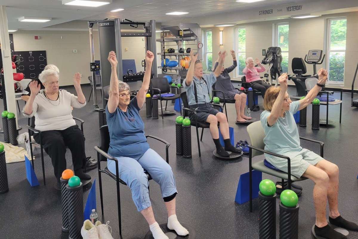 Residents stretching while sitting in chairs at the gym at Chapel Hill Senior Living