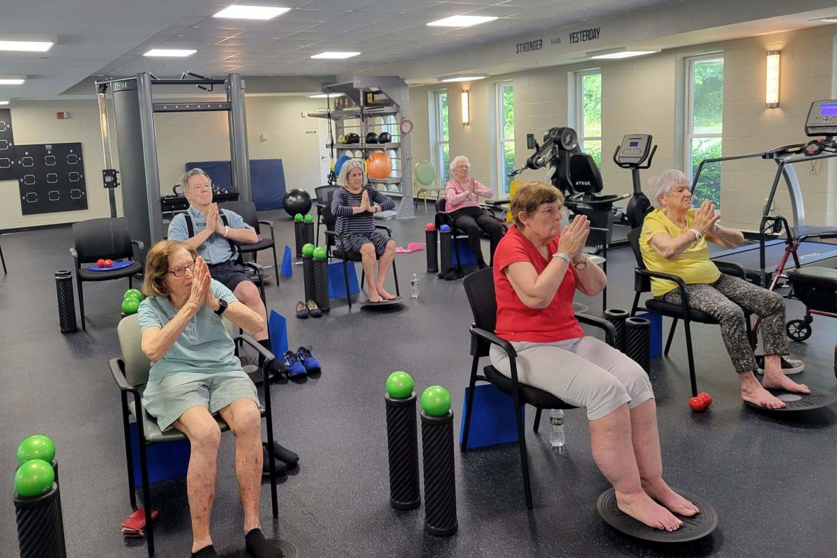 Residents stretching while sitting in chairs at the gym at a Meridian Senior Living community