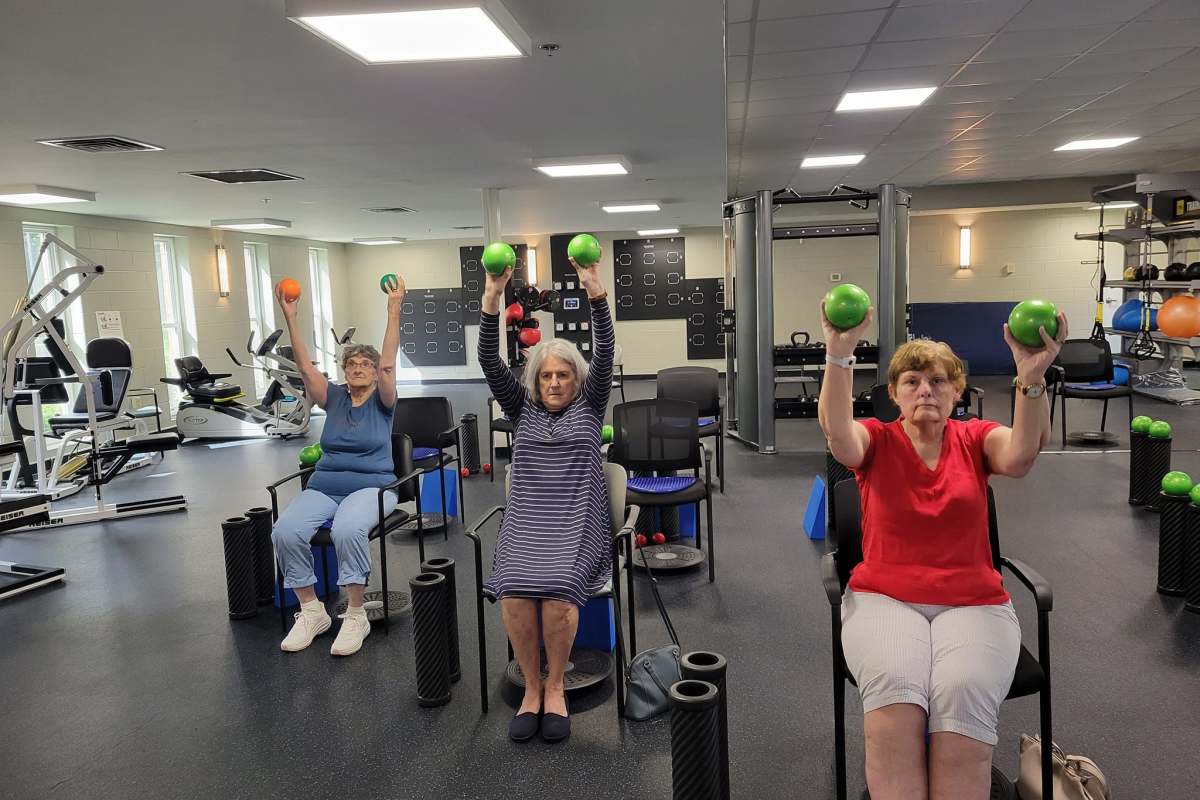 Residents stretching while sitting in chairs at the gym at a Meridian Senior Living community