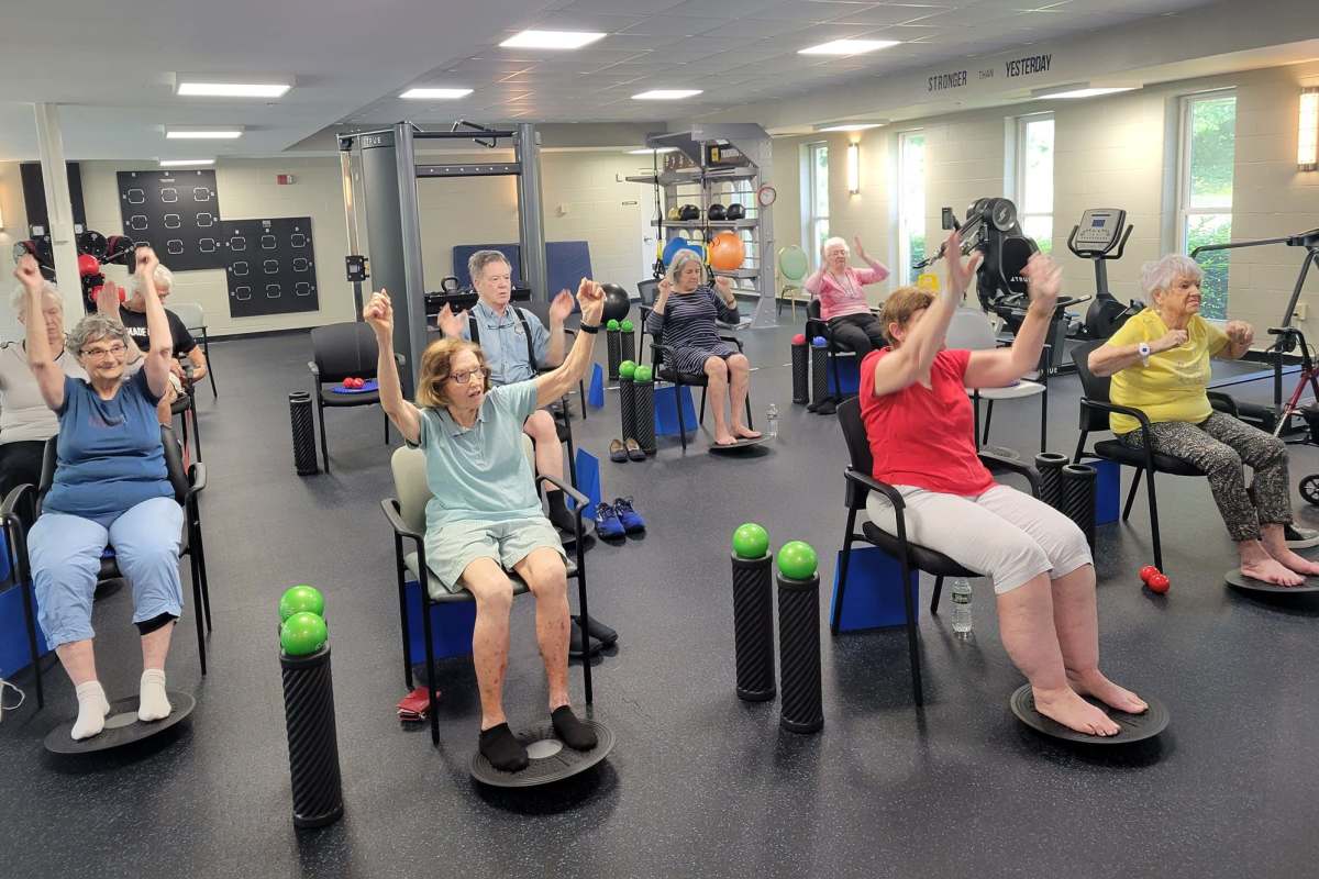 Residents stretching while sitting in chairs at the gym at a Meridian Senior Living community