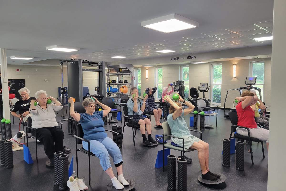 Residents stretching while sitting in chairs at the gym at a Meridian Senior Living community