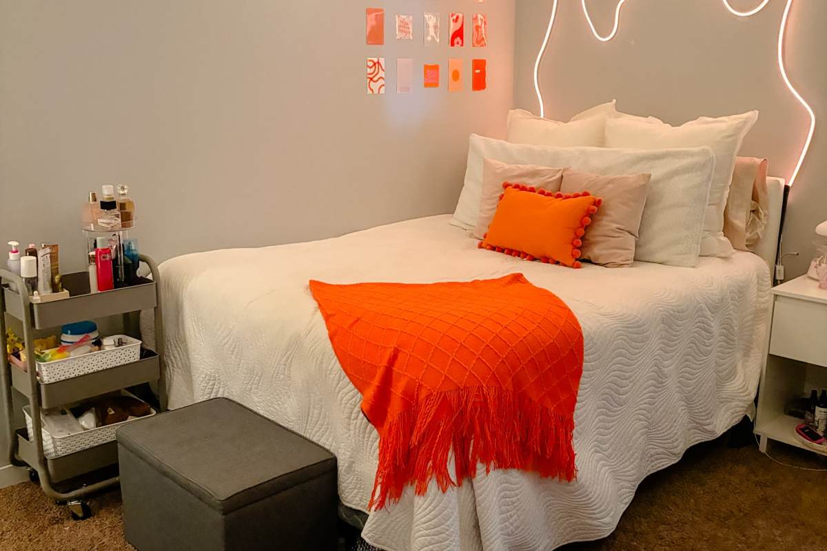 Full size bed with orange throw pillow and blanket at Lofts @ 1633 in Mankato, Minnesota