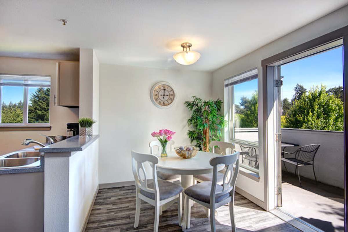 Well lit and open kitchen and dining area with hard wood flooring at Briarstone in Tacoma, Washington