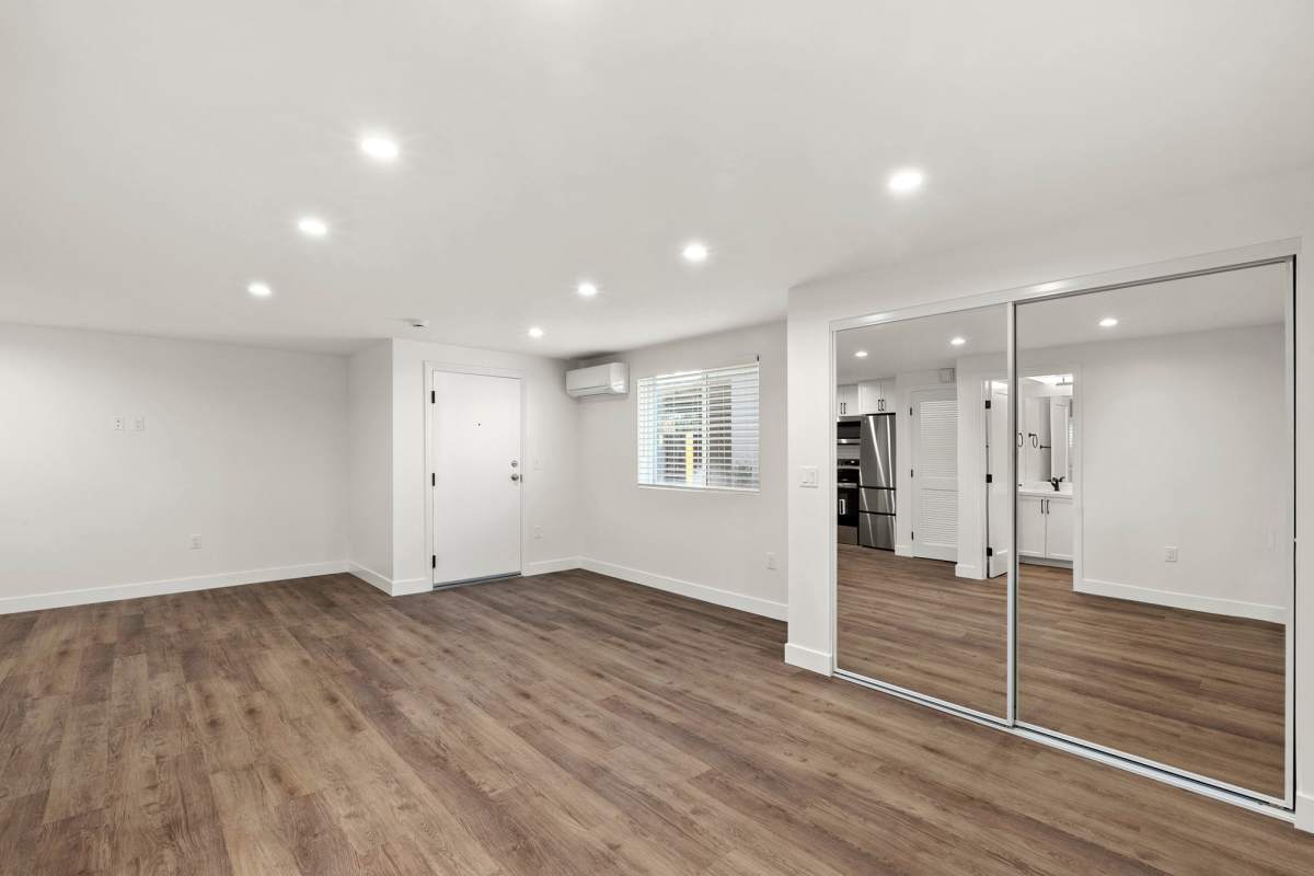 Apartment with large sliding glass door and wood-style flooring at Los Feliz Village in Los Angeles, California