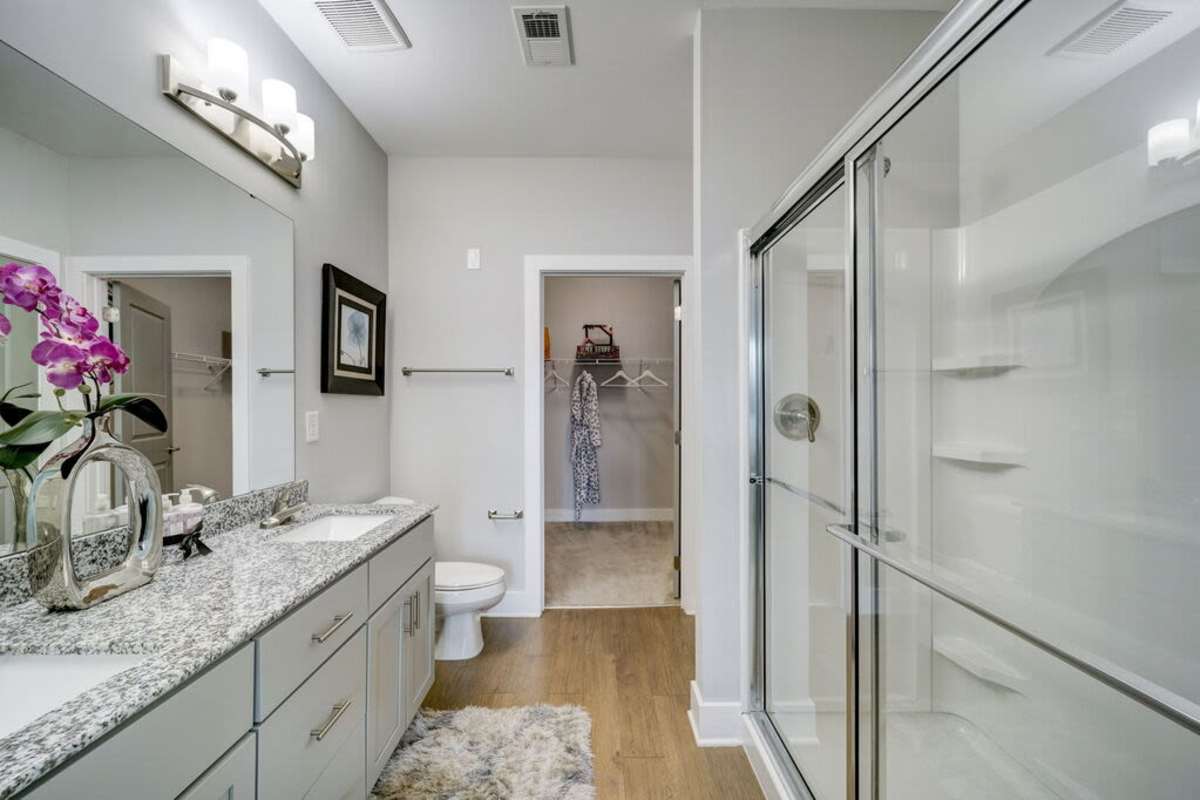 Spacious bathroom with two sinks and a huge mirror and a glass wall shower area at Century Park Place in Morrisville, North Carolina