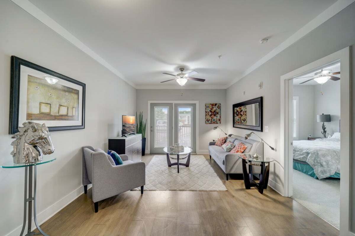 Spacious living room showcasing the furniture and door to outside with another door to the bedroom at Century Park Place in Morrisville, North Carolina