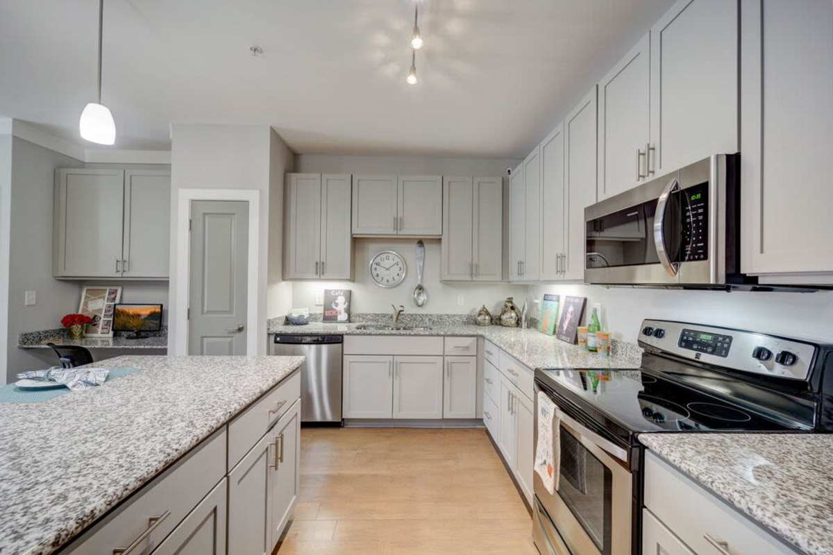 Spacious kitchen area with hanging cabinets, modern appliances and a kitchen island bar at Century Park Place in Morrisville, North Carolina