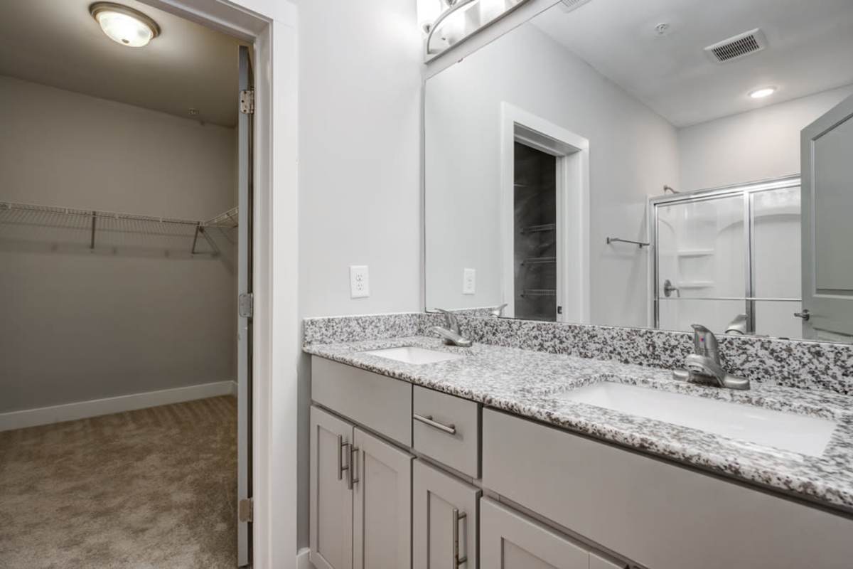 An empty bathroom with glass wall shower area reflecting from the huge mirror of the sink at Century Park Place in Morrisville, North Carolina