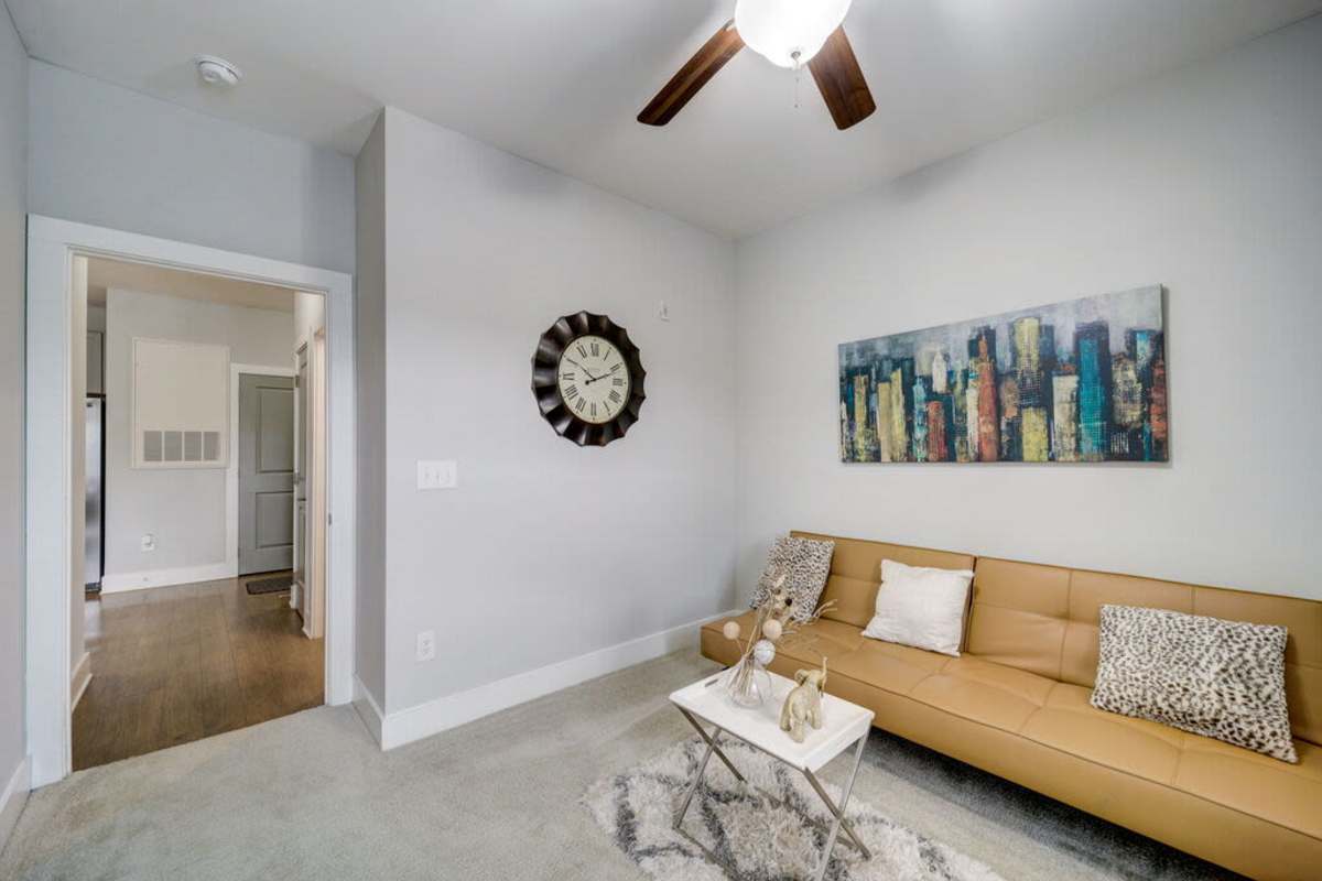 A room with beige colored sofa with three throw pillows and a painting at Century Park Place in Morrisville, North Carolina