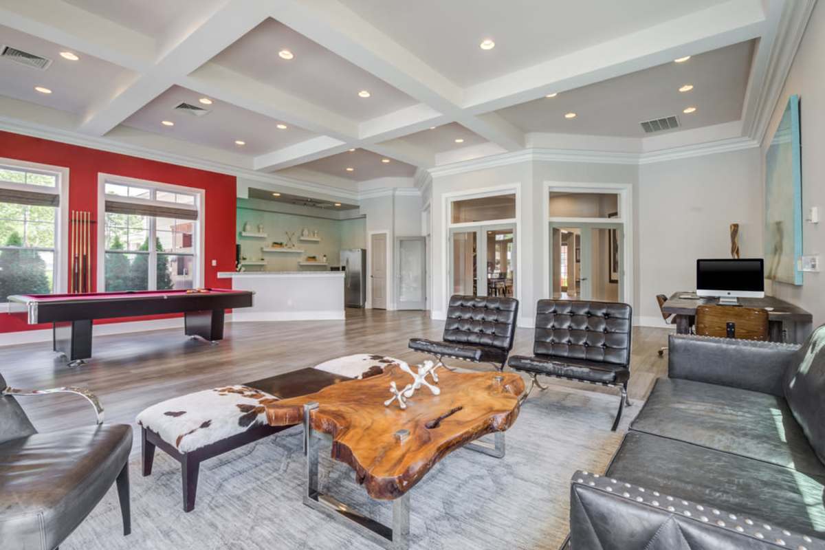 A spacious living room featuring a pool table and comfortable couches arranged for relaxation and entertainment at Century Park Place in Morrisville, North Carolina