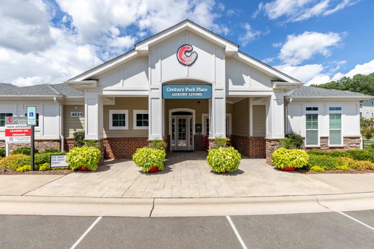 Front entrance of a community center, featuring large doors and welcoming signage, surrounded by greenery at Century Park Place in Morrisville, North Carolina