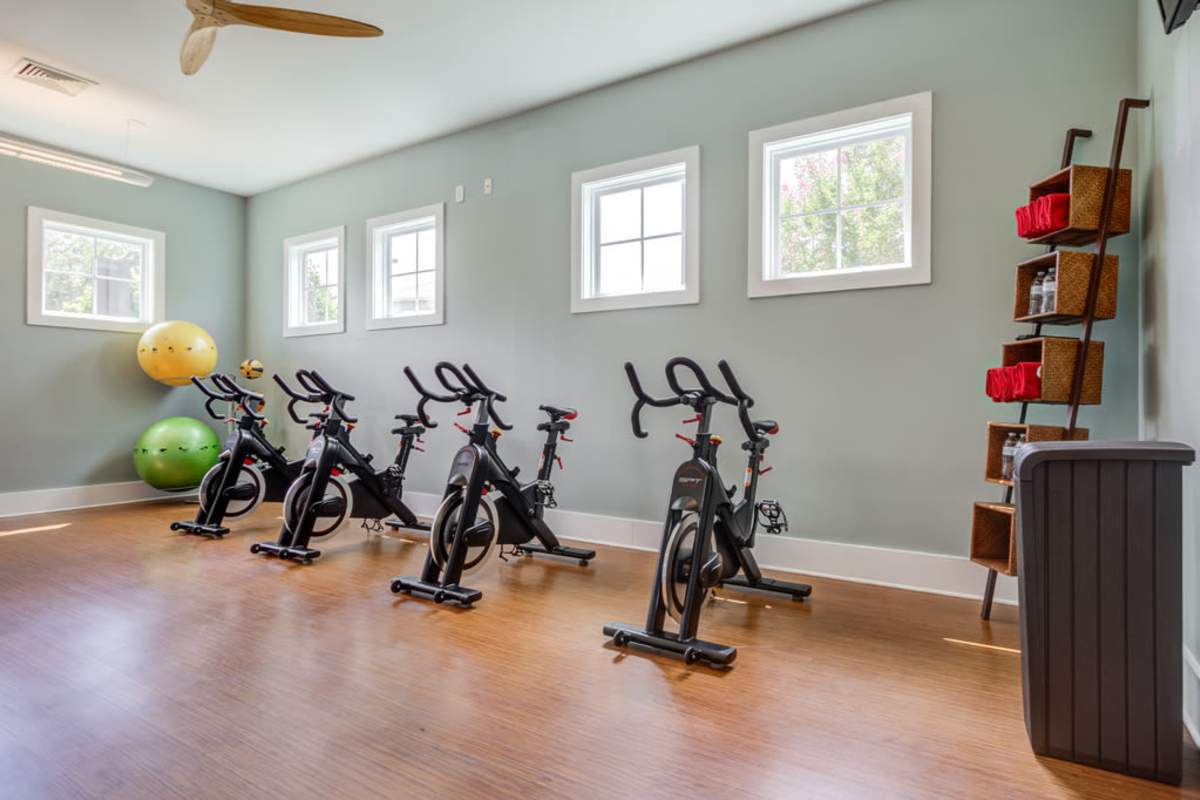 A gym room featuring several exercise bikes and a ceiling fan for ventilation at Century Park Place in Morrisville, North Carolina