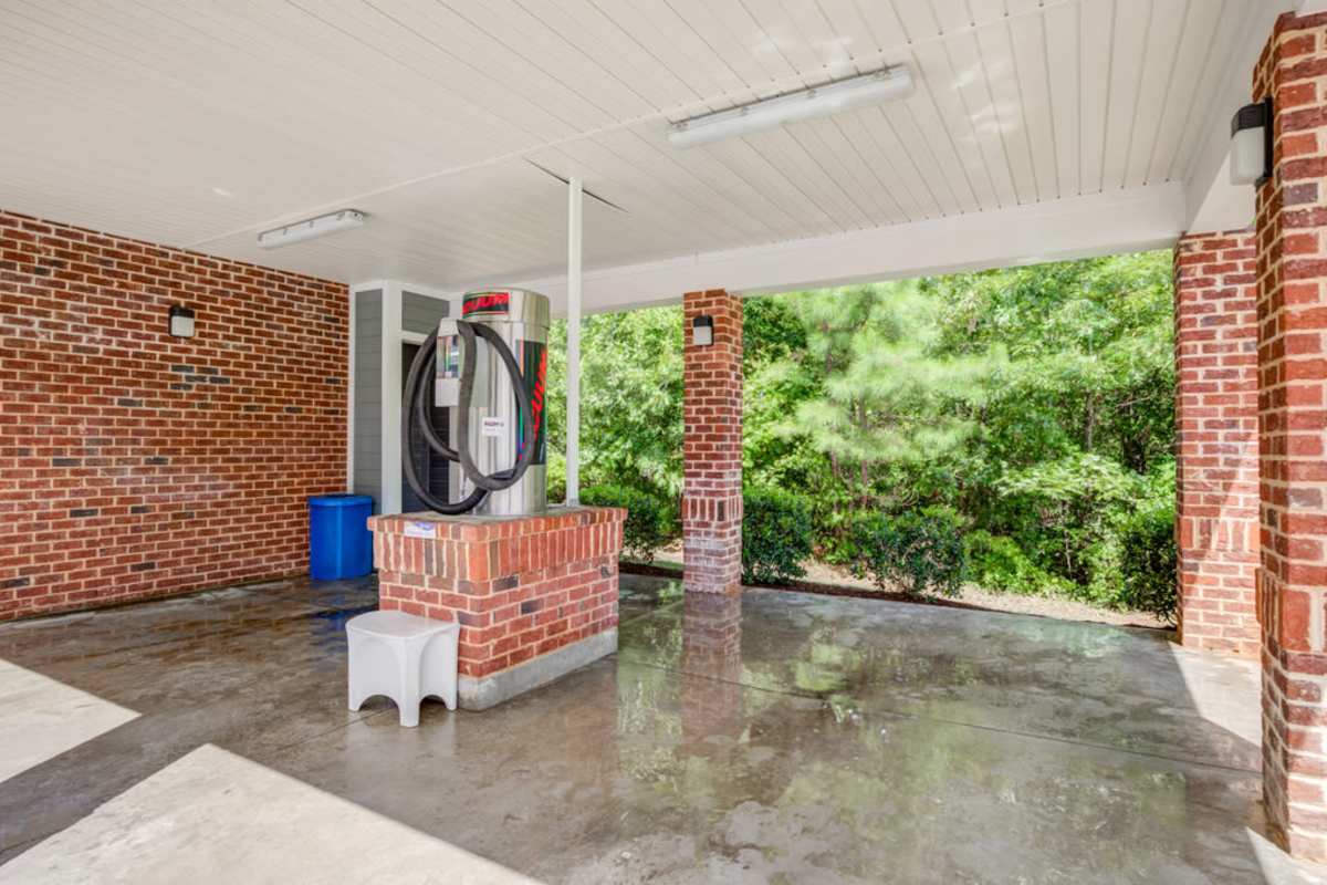 A brick building featuring a gas pump and a water fountain in front, set against a clear blue sky at Century Park Place in Morrisville, North Carolina