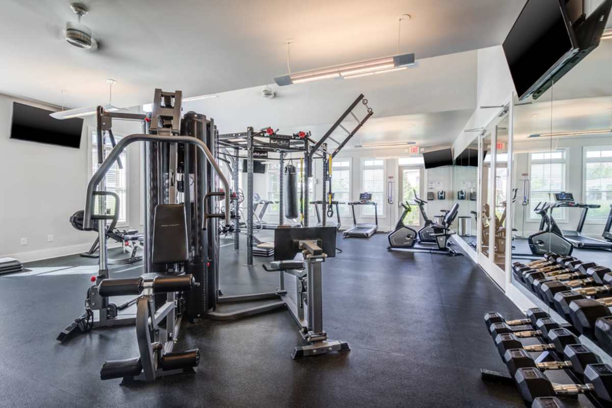 A gym room featuring various exercise equipment and large mirrors on the walls at Century Park Place in Morrisville, North Carolina