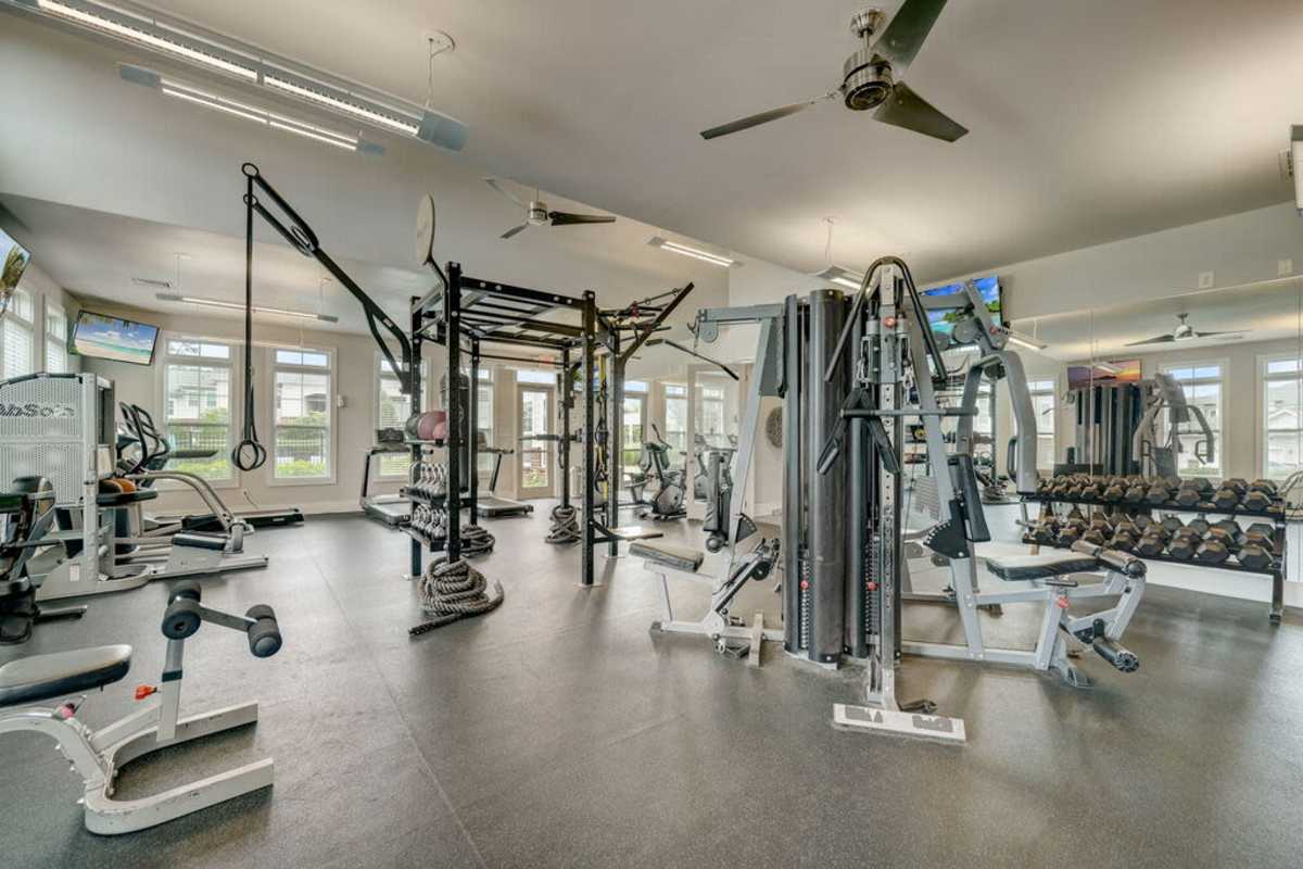 A gym room featuring various exercise equipment and a ceiling fan for ventilation at Century Park Place in Morrisville, North Carolina