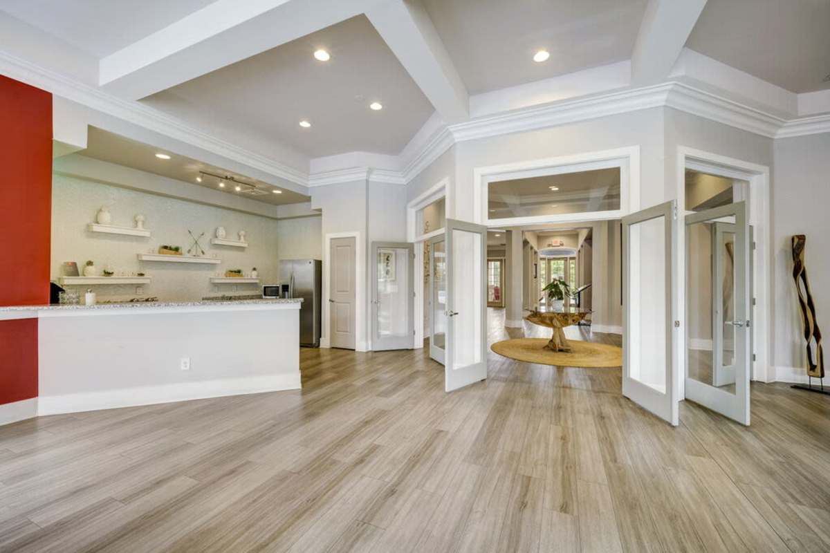 A spacious living room featuring hardwood floors and vibrant red walls, creating a warm and inviting atmosphere at Century Park Place in Morrisville, North Carolina