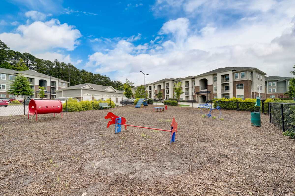 Playground featuring swings, slides, and play structures surrounded by greenery at Century Park Place in Morrisville, North Carolina