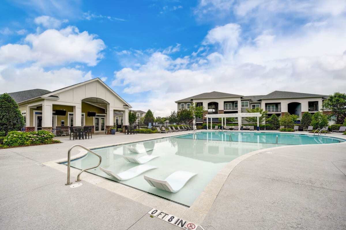 The pool area featuring lounge chairs and palm trees in a sunny setting at Century Park Place in Morrisville, North Carolina