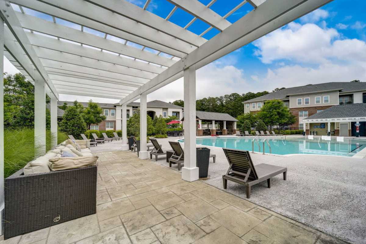 Outdoor swimming pool with beach chairs for sun bathing and couches at Century Park Place in Morrisville, North Carolina