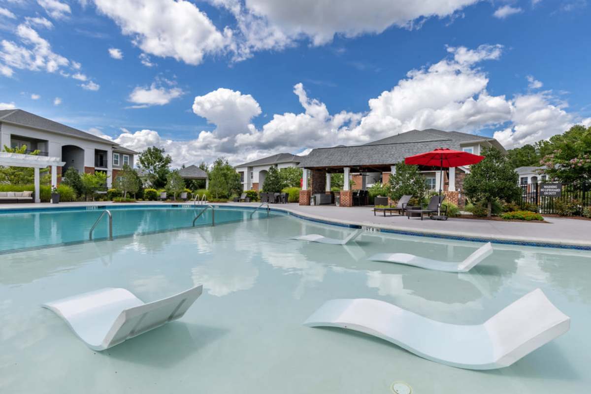 A photo of outdoor swimming pool with beach chairs inside the pool at Century Park Place in Morrisville, North Carolina