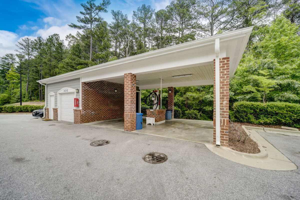 A brick building with a gas pump beside a water fountain, creating a welcoming stop for visitors at Century Park Place in Morrisville, North Carolina
