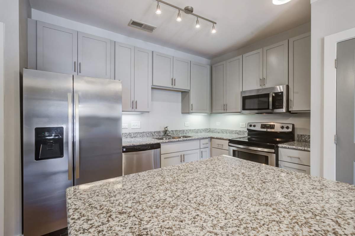 A photo of kitchen area with hanging cabinets, island bar and modern appliances at Century Park Place in Morrisville, North Carolina