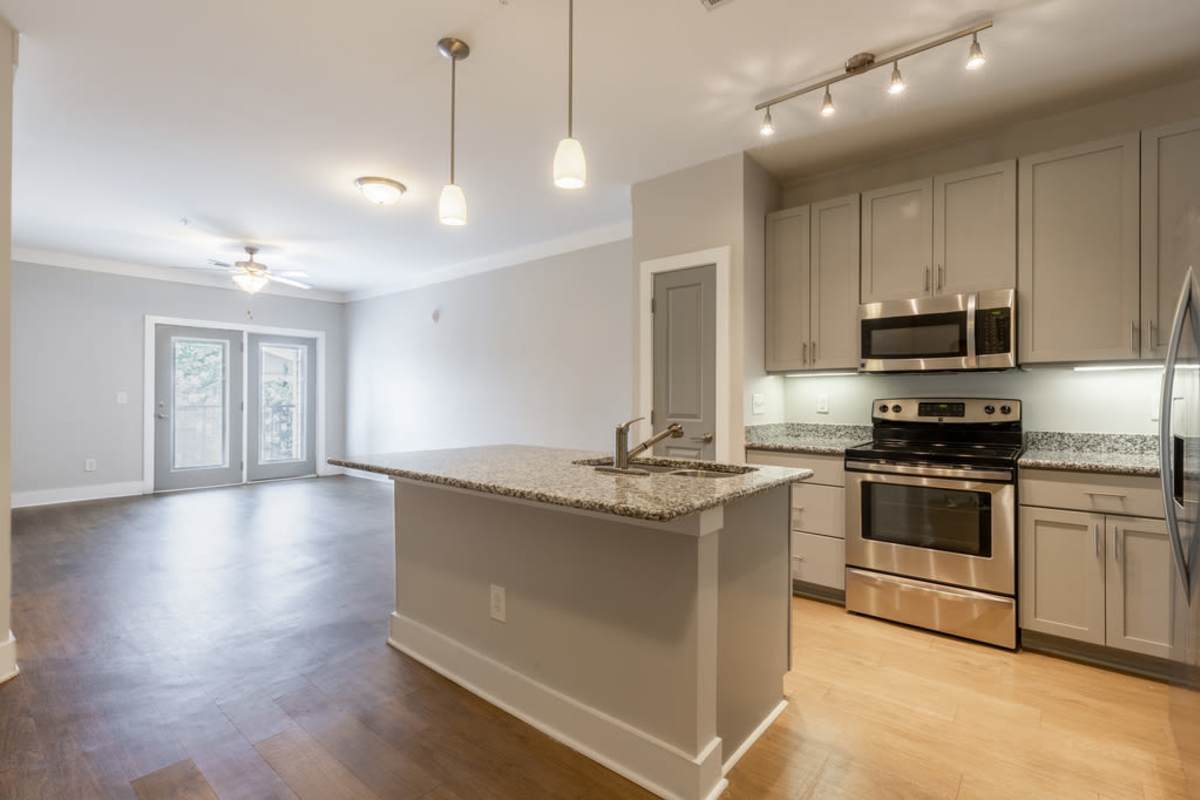 An empty kitchen area that showcases an empty living room at Century Park Place in Morrisville, North Carolina