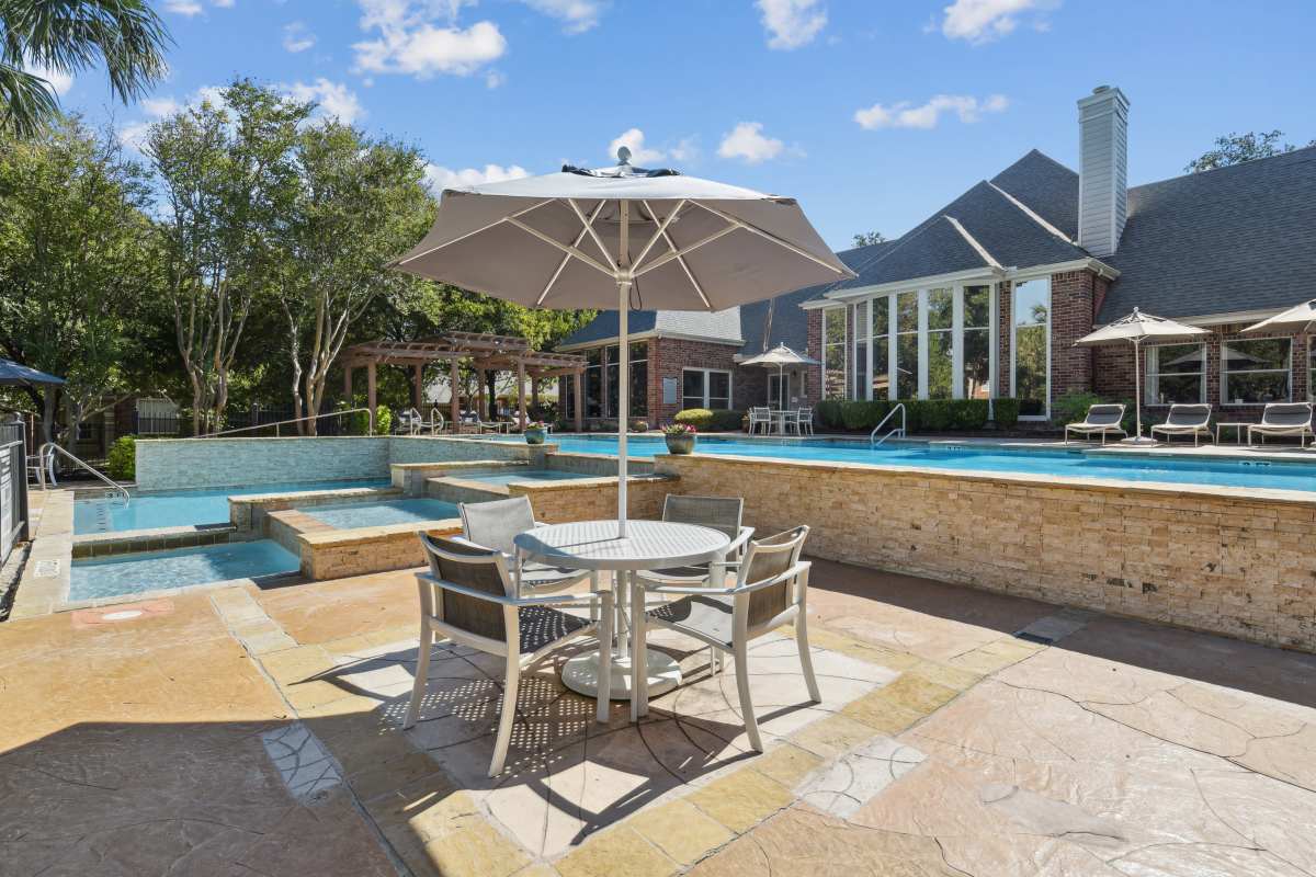 Outdoor Seating Area With An Umbrella And A View Of The Pool at Whispering Creek Villas, San Antonio, Texas