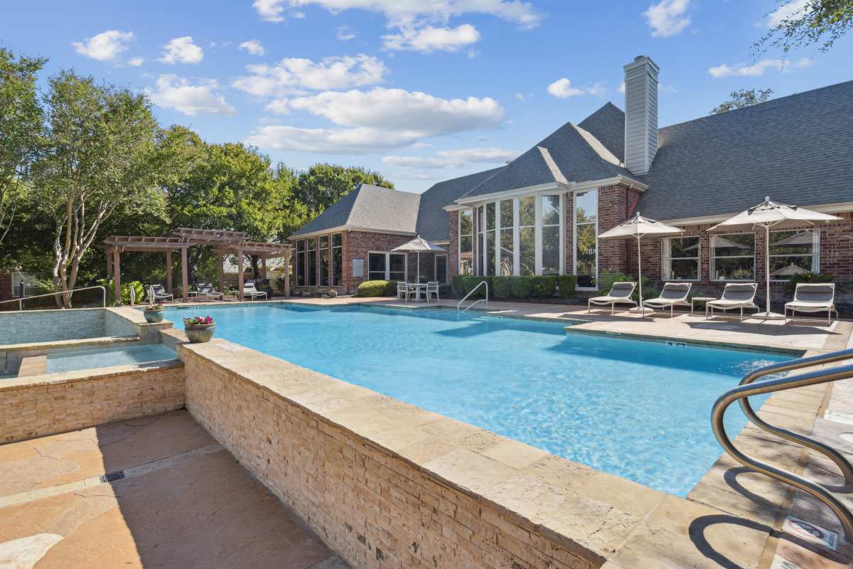 Luxurious Swimming Pool Area With A Large Building And Lush Green Trees at Whispering Creek Villas, San Antonio, Texas