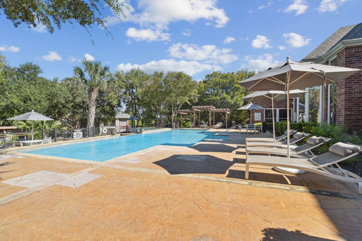 Resort-Style Swimming Pool With Lounge Chairs And Umbrellas at Whispering Creek Villas, San Antonio, Texas