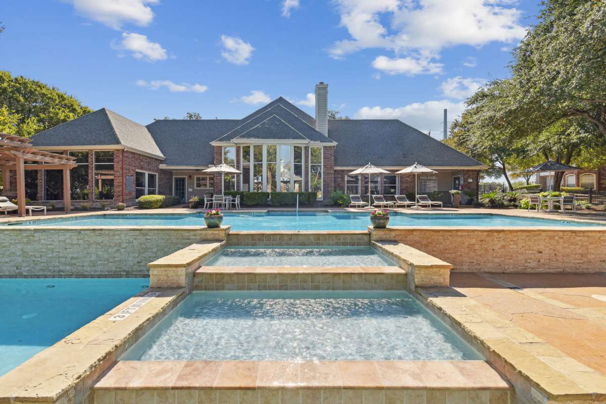 Grand Swimming Pool With A Large Building In The Background at Whispering Creek Villas, San Antonio, Texas