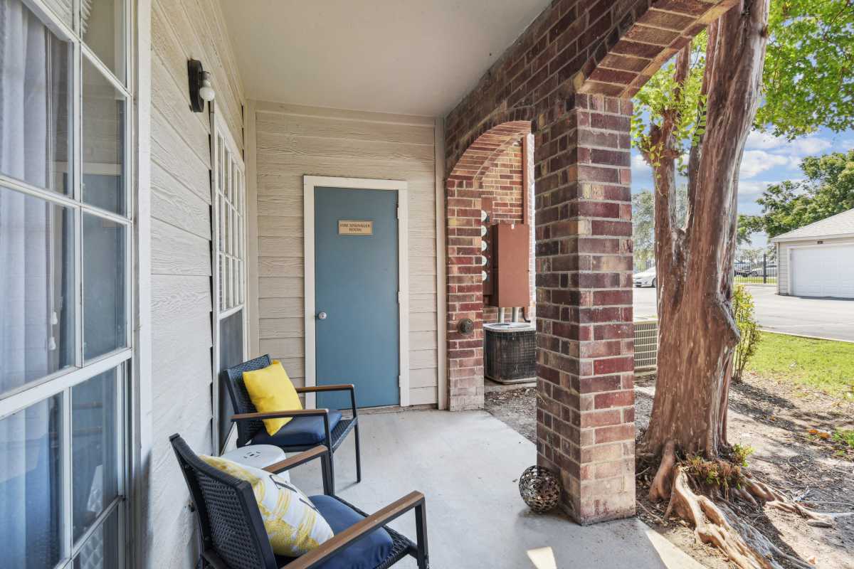 Covered Porch With Seating And A Brick Archway at Whispering Creek Villas, San Antonio, Texas