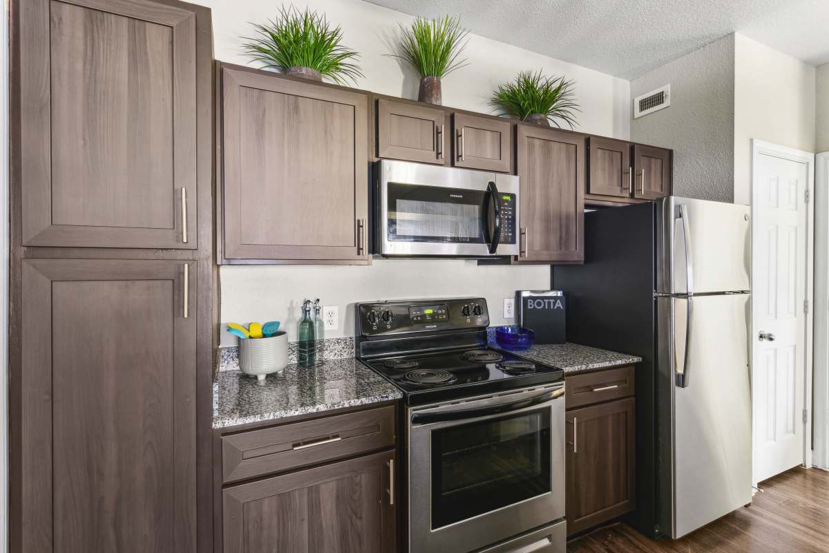Stylish Kitchen With Dark Wood Cabinets And Stainless Steel Appliances at Whispering Creek Villas, San Antonio, Texas