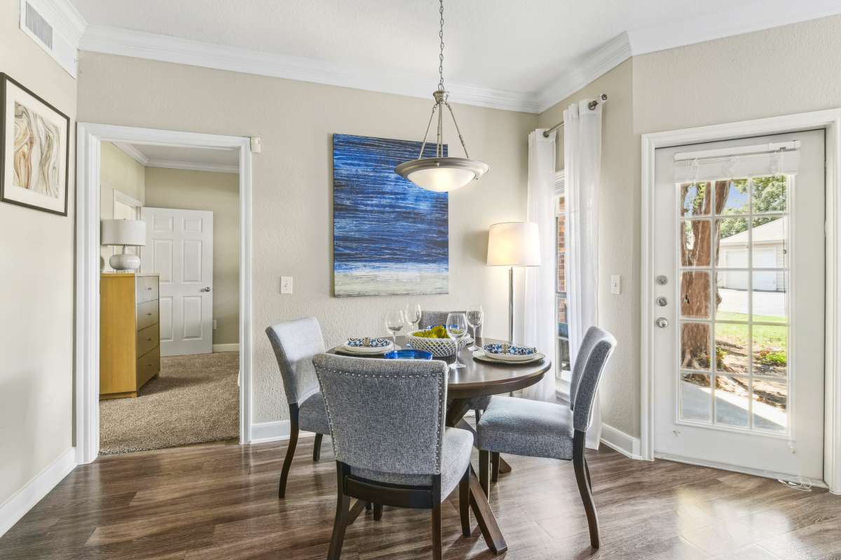 Dining Area With A Round Table And Chairs Next To A Door Leading Outside at Whispering Creek Villas, San Antonio, Texas