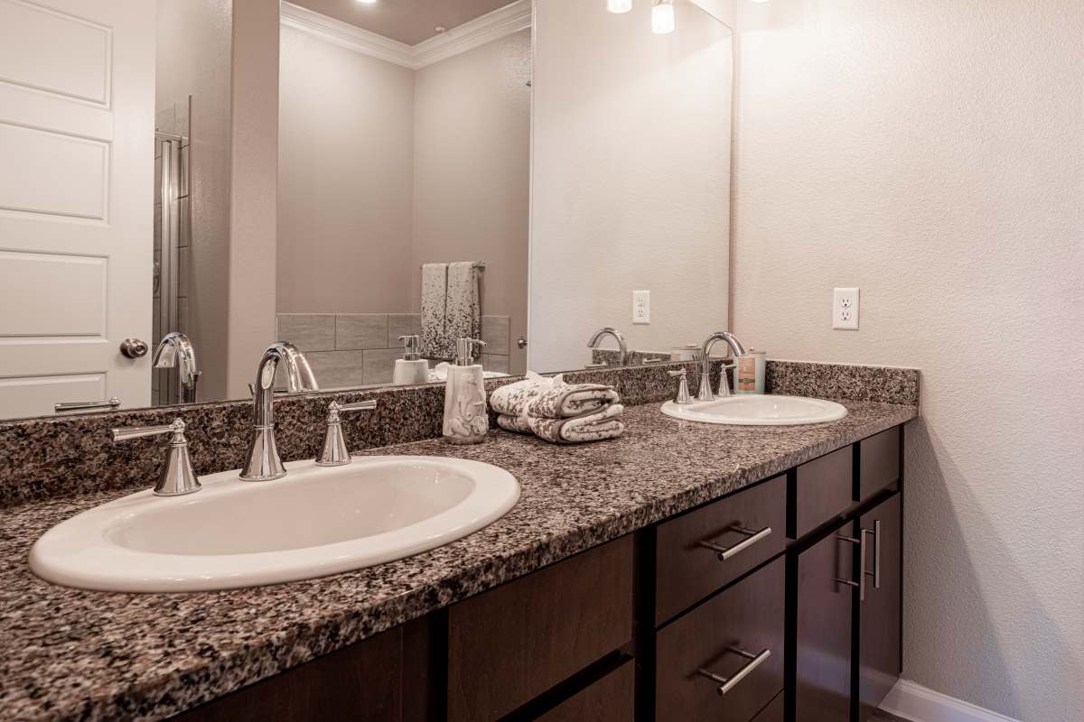 Bright bathroom sink, mirror and wood cabinet at Century Travesia in Austin, Texas