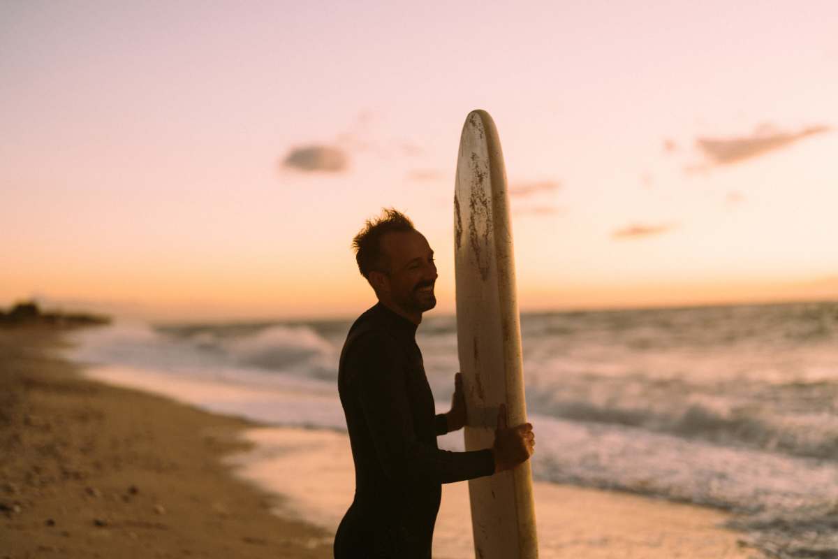 Man holding a surfboard at Tower24 Ponto Beach in Carlsbad, California
