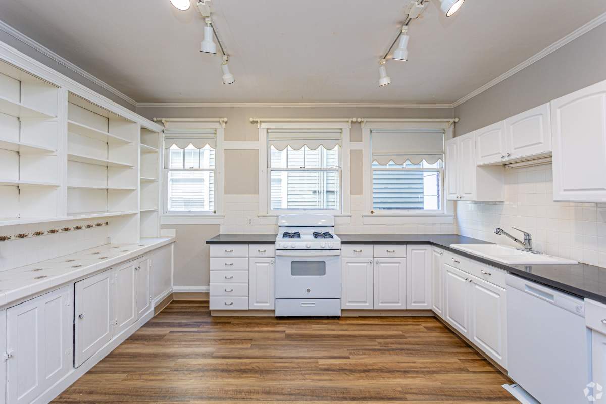 A fully equipped kitchen with carpeted flooring, white tile backsplash and a dishwasher at The Miller in Tacoma, Washington