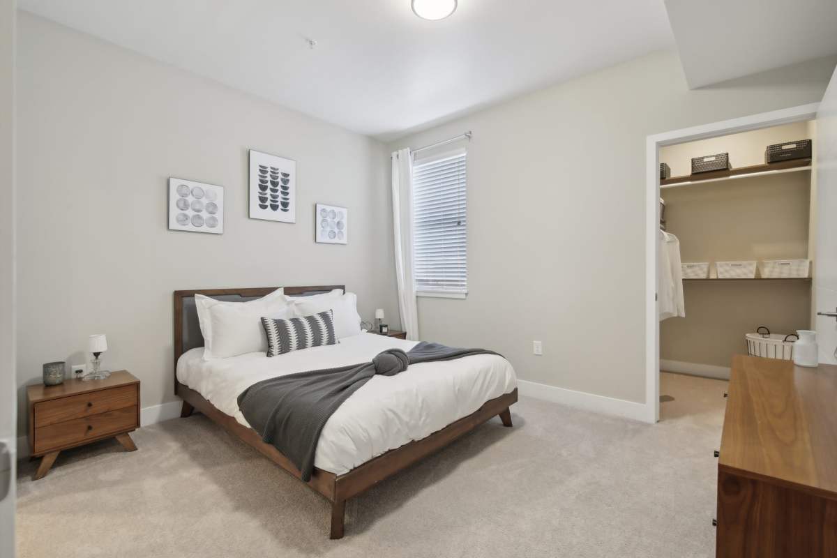 Elegant bedroom with a cozy bed, decorative pillows, and bedside tables, featuring soft lighting and a calming color palette at The Wyatt Apartments in Fort Collins, Colorado.