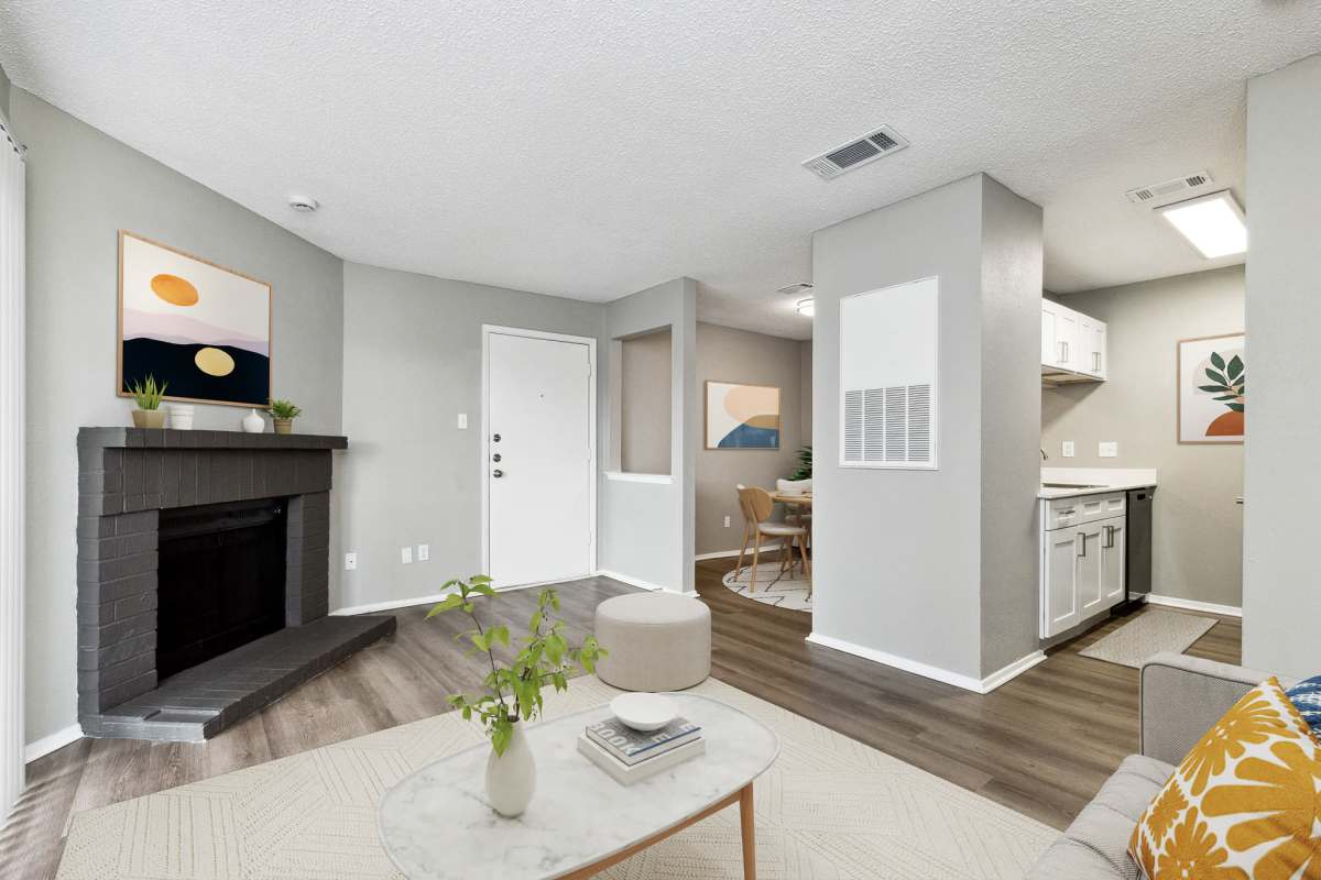 Model living area with fireplace and wood-style flooring at Hunters Glen in Killeen, Texas