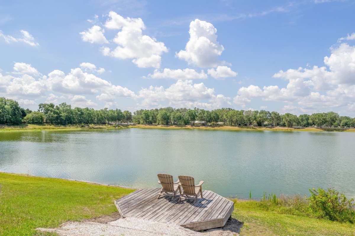 Lakeside deck with two wooden chairs overlooking calm water at Century Lakehouse, Plant City, Florida
