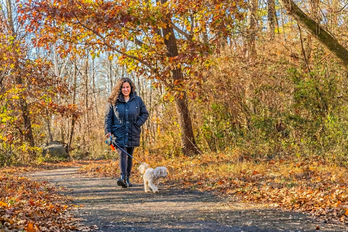 Happy resident and dog walking on trail Lee Overlook Apartments in Centreville, Virginia