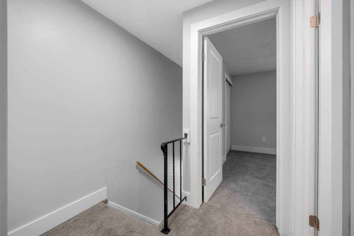 Staircase leading to carpeted hallway at Valley Brook Townhomes in Rochester, New York