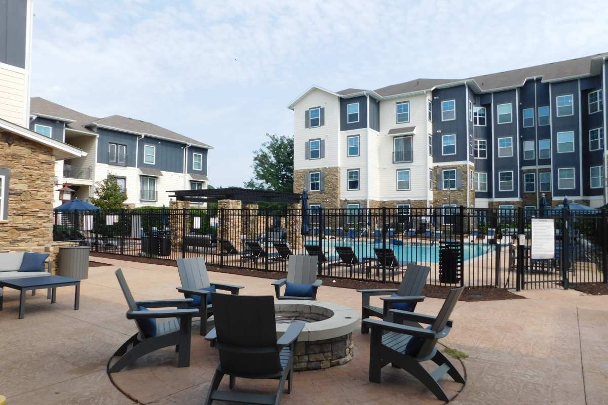 Outdoor pool area with fire pit seating and apartment community views at The Den in Columbia, Missouri