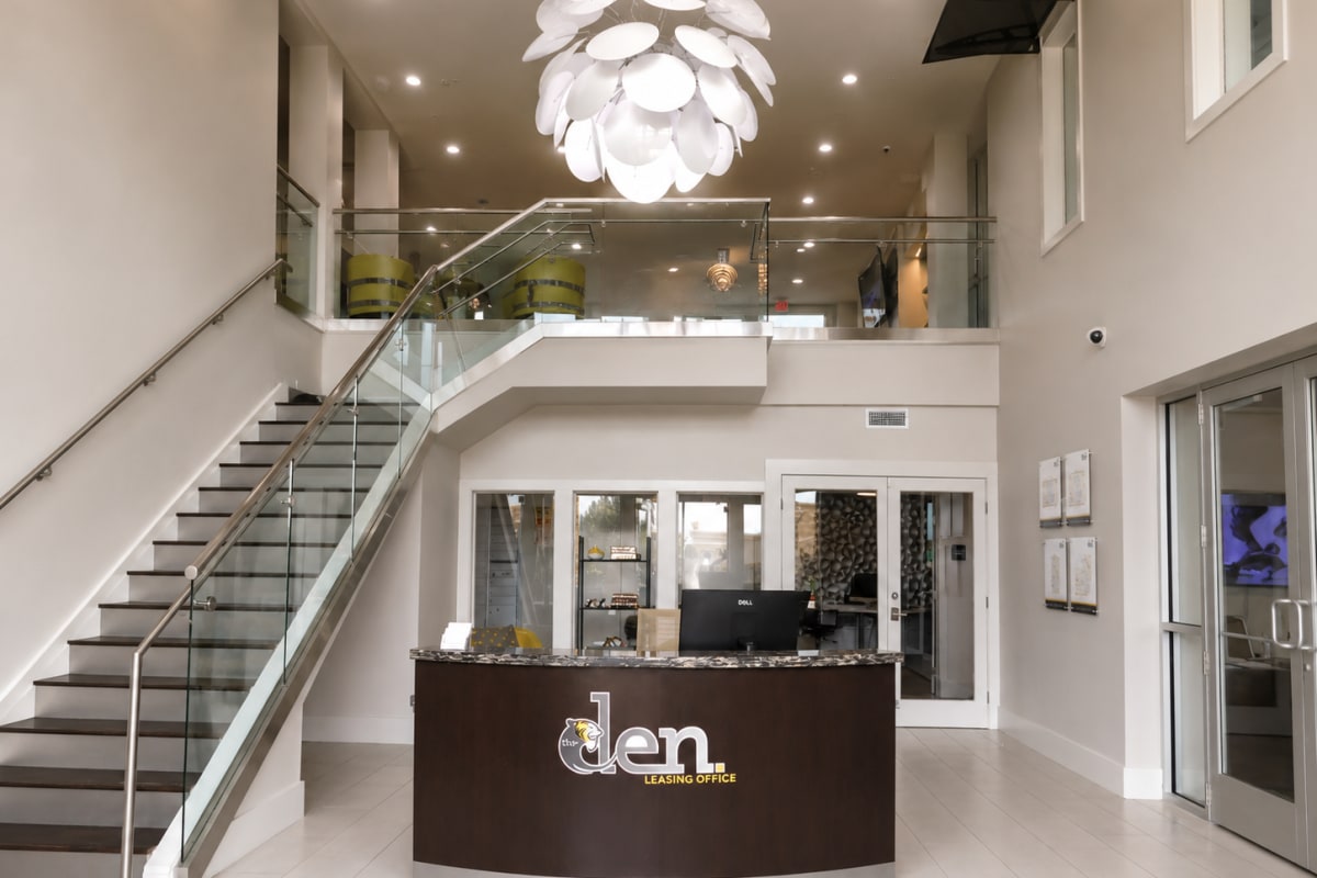 Modern clubhouse lobby with staircase and reception desk at The Den in Columbia, Missouri