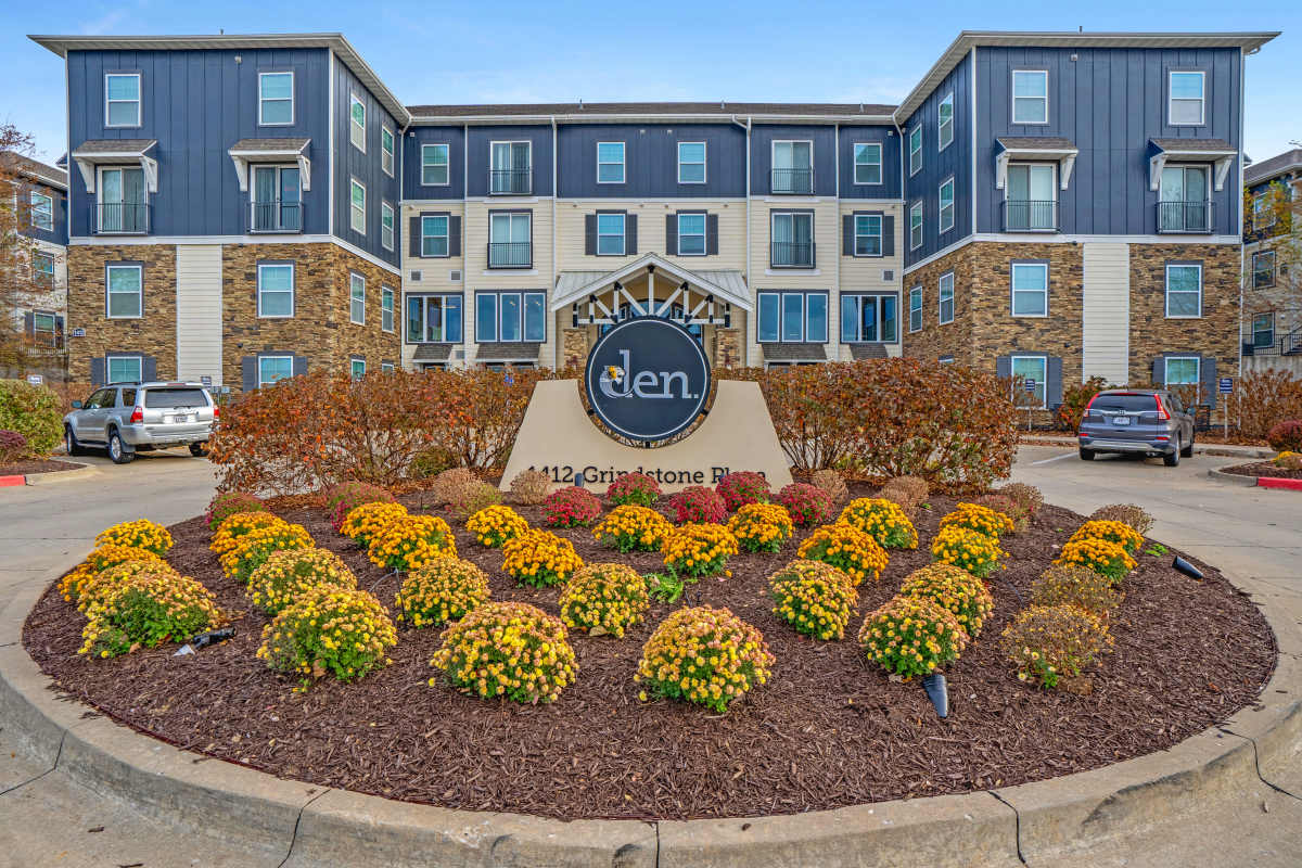 Community entrance sign and apartment building exterior at The Den in Columbia, Missouri