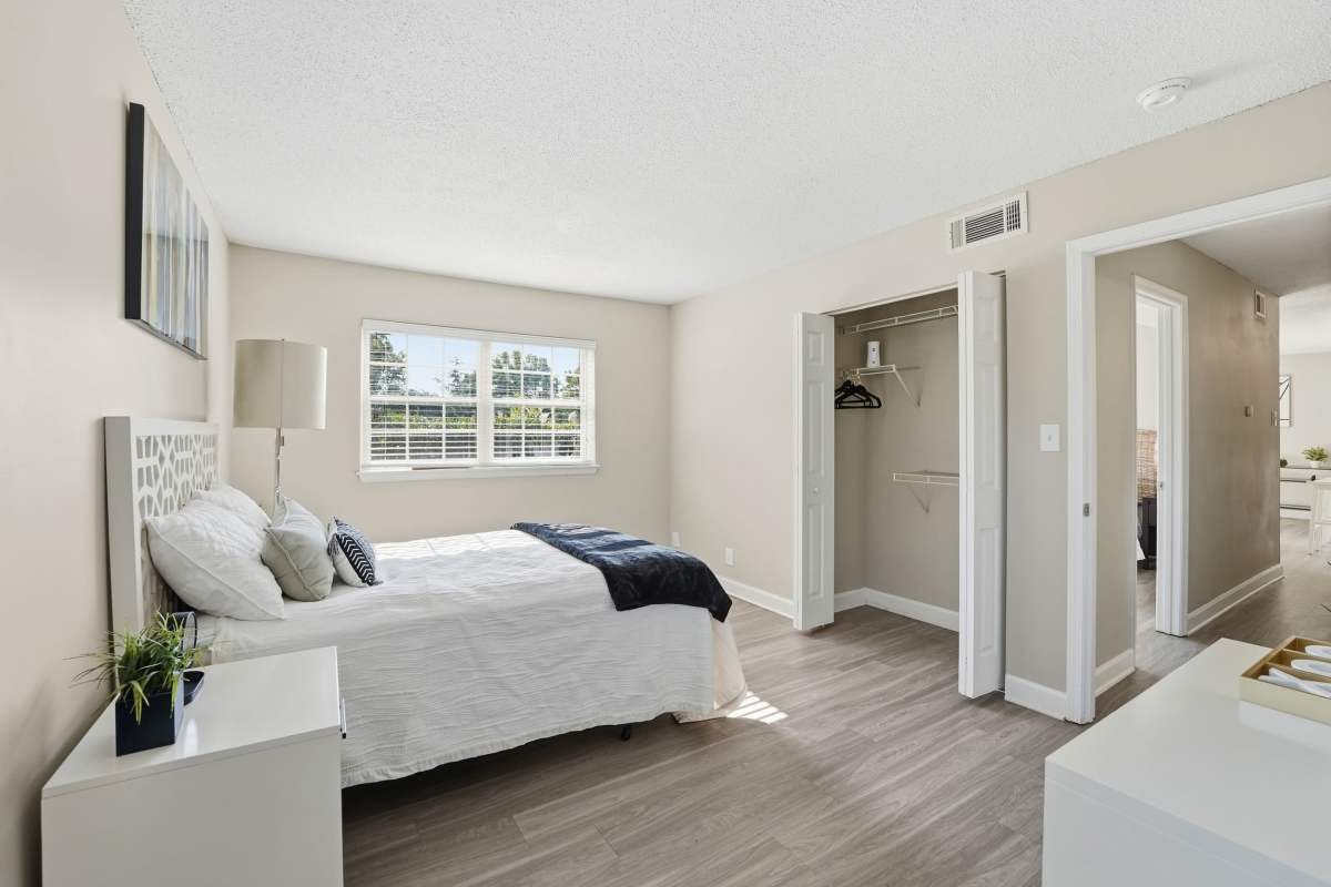 Bed with white quilt and decorative pillows at Collins Crossing Apartments in Carrboro, North Carolina