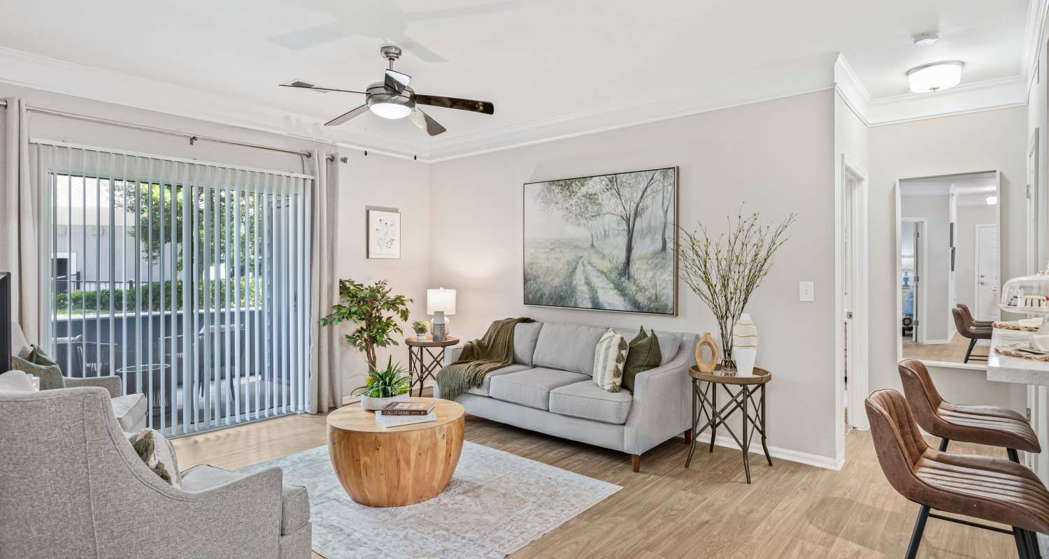  Stylish living room with a gray sofa, artwork, and bright decor. Light wood floors, plants, and natural light at Retreat at Johns Creek in Duluth, Georgia