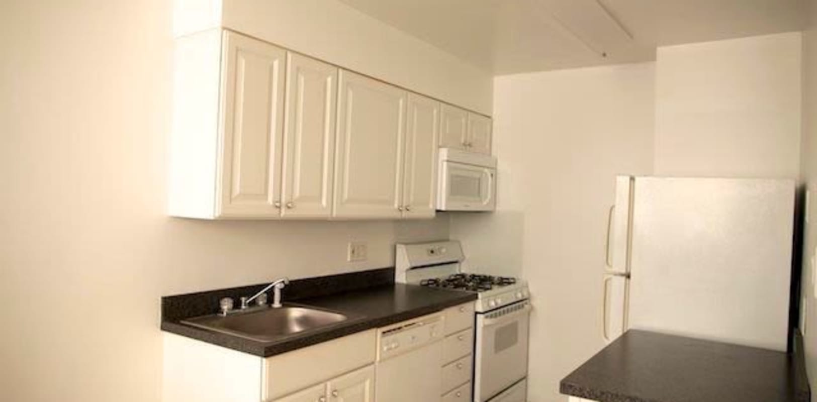A clean kitchen with black countertops and nice white cabinets at Marina Park Apartments in Collingswood, New Jersey