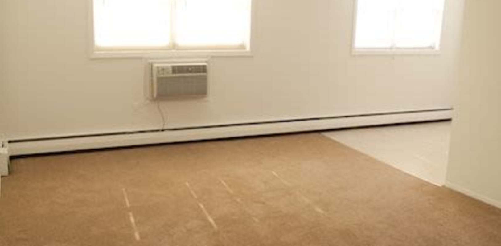 Large living room with carpeted floors and an ac unit at Marina Park Apartments in Collingswood, New Jersey