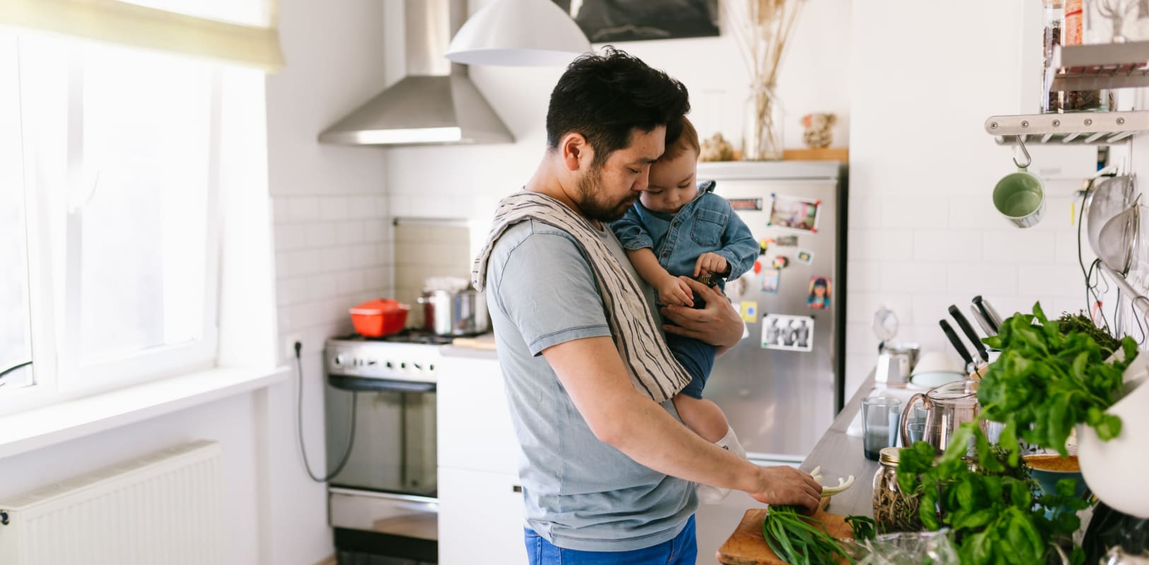 Father holding his son and cooking a meal in their home in Hollywood Terrace in Linden, New Jersey